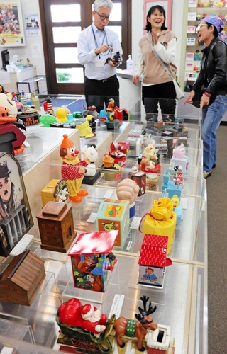 「そう動くのか」。思わぬ仕掛けに笑顔になる貯金箱展＝尼崎市西本町北通３