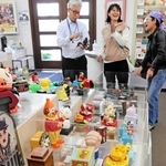 「そう動くのか」。思わぬ仕掛けに笑顔になる貯金箱展＝尼崎市西本町北通３