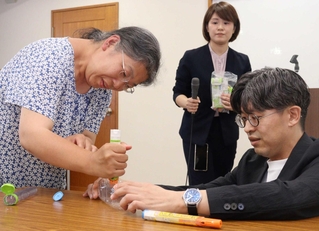 エピペンの打ち方を参加者（左）に教える医師の平瀬敏志さん（右）＝西宮市六湛寺町
