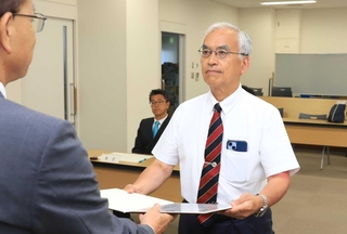 猪名川町長選で再選され、当選証書を受け取る岡本信司氏（右）＝猪名川町役場