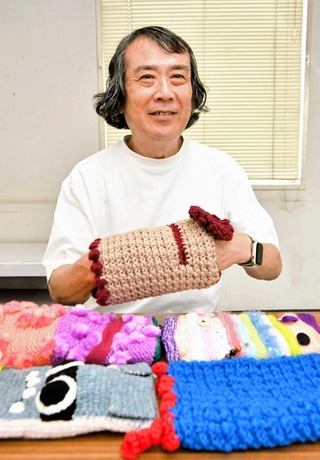 認知症マフを手にするオンボードの山本雅彦理事長＝西宮市和上町