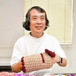 認知症マフを手にするオンボードの山本雅彦理事長＝西宮市和上町