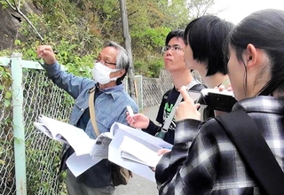 戦闘機の工場だったという甲陽園の地下壕へ足を運び、市民団体のメンバーから説明を受ける鳴尾高校放送部員（提供）