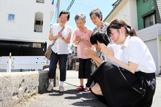 橋がこの場所にある最後の８月６日。阪神大空襲を経験した３姉妹と一緒に手を合わせる（手前右から）山口伊織さんと三木さゆりさん＝西宮市学文殿町