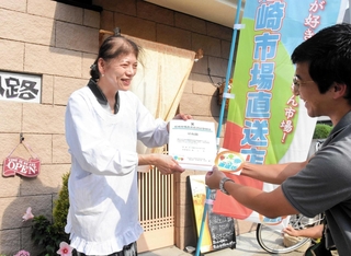 尼崎市職員から直送店の登録証などを受け取る「はね路」店主の稲垣真知子さん＝同市塚口町１