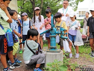防災井戸のポンプを押して水を出す児童＝伊丹市南野６