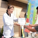 尼崎市職員から直送店の登録証などを受け取る「はね路」店主の稲垣真知子さん＝同市塚口町１