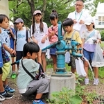防災井戸のポンプを押して水を出す児童＝伊丹市南野６