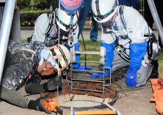 尼崎市の下水道管を調査する作業員ら。内部の水深が増して作業は中断となった＝２５日午後、尼崎市東松島町
