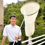 山がすぐそばまで迫る学校敷地内で網を手にする木下翔太郎さん＝西宮市鷲林寺