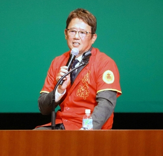 創立５０周年記念の赤いユニフォームを着て在校生の質問に答える古田敦也さん＝川西市火打１