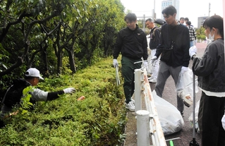 川辺の植栽帯で空き缶などを拾う市民ら＝１日午前、尼崎市東難波町４