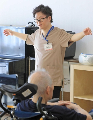 高齢者施設で入居者の体操を指揮する多田駿介さん＝猪名川町伏見台１