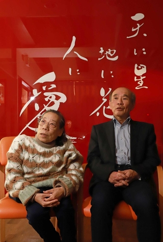 三和之家を経営する田山華栄会長（左）と夫の幸雄社長。施設の真っ赤な壁には大切にする言葉が記されている＝尼崎市内（撮影・小林良多）
