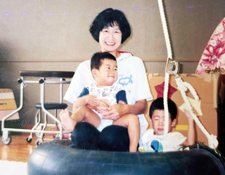 井上貴行さんを抱える母多永子さんと兄の正行さん＝１９９４年８月（井上さん提供）
