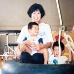 井上貴行さんを抱える母多永子さんと兄の正行さん＝１９９４年８月（井上さん提供）