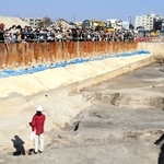 西宮中央運動公園で見つかった遺構について学芸員の説明に耳を傾ける多くの市民ら＝西宮市河原町