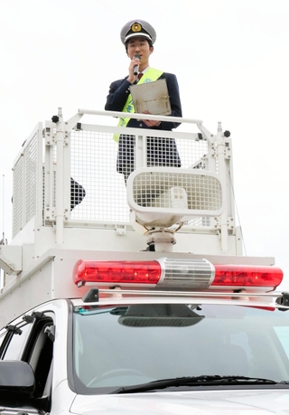 ＤＪポリスになりきって、交通安全を呼びかける宝塚北高の生徒＝宝塚市すみれガ丘４