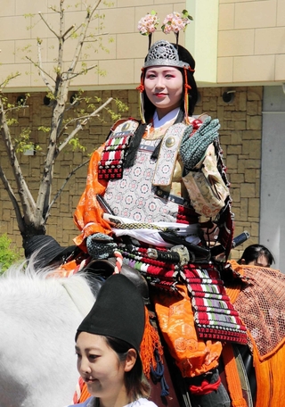 白馬にまたがり、沿道の観衆に手を振る巴御前役の奥西愛美さん＝川西市美園町