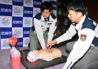 「めぐる君」を実演する尼崎市消防局の眞造務救急課長（右）と黒川貴紀消防士長＝市役所