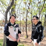 伊丹市みどり自然課の職員から話を聞く松永Ｋ三蔵さん（右）。頭上にはカワウが巣を作っている＝伊丹市昆陽池３