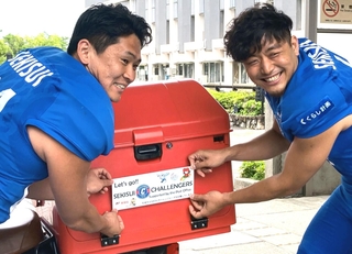 尼崎市内を走る郵便配達のバイクにチームの応援ステッカーを貼る阿部拓朗選手（左）と佐藤敏基選手＝尼崎市役所