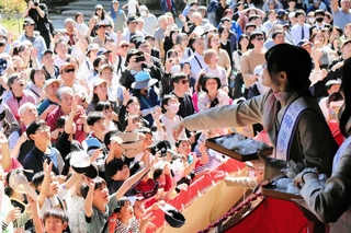 餅まきで一生懸命に手を伸ばす子どもら＝川西市満願寺町