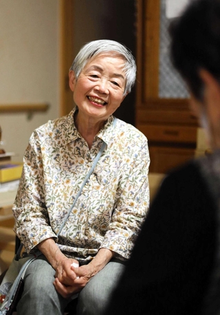 利用者と話す滝本桂子さん。自転車も車も乗れないから、８０歳になっても歩いて訪問している＝尼崎市内