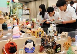 気になった貯金箱を取材する（左から）林莉香さん、西川悠さん、大川琉輝さん＝尼崎市西本町北通３