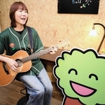 商店会「甲子園けやき散歩道」の公式テーマソングを手がけた高田志麻さん。隣にいるのは同会のキャラクター「けやきくん」＝西宮市鳴尾町１