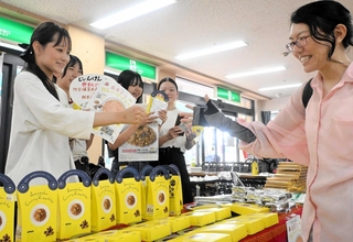 大学生は販売会に訪れた買い物客らに防災食をアピールし、じゃんけんで交流した＝尼崎市潮江１