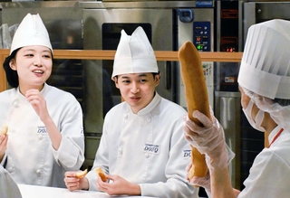 社員から説明を聞き、フランスパンを試食する学生ら＝西宮市甲子園八番町