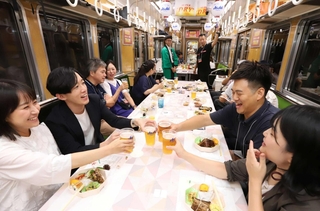 走り出した夜の車内で乾杯。ビール電車を楽しむ参加者＝川西市内