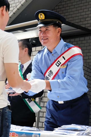 通行人に啓発グッズを手渡す福留孝介さん＝芦屋市大原町