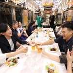 走り出した夜の車内で乾杯。ビール電車を楽しむ参加者＝川西市内