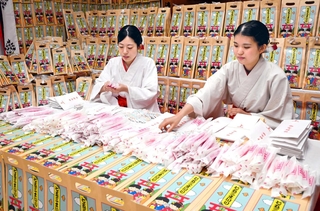 千歳あめを袋に詰める巫女＝西宮市社家町