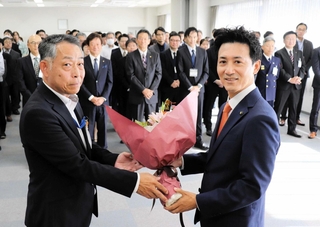 職員から花束を受け取る川西市の越田謙治郎市長（右）＝市役所