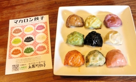 焼きたてのマカロンギョーザと、リーフレット。９色の並べる順は決まっており、リーフレットの裏面には食材を全て記載している＝神戸市東灘区深江北町１