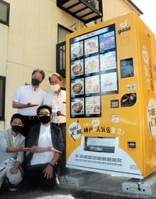 冷凍食品の自販機「ＴＡＢＥ　ＫＯＢＥ」（食べ神戸）の第１弾を設置した川原裕剛さん（２列目左）ら＝神戸市東灘区魚崎南町４のトミーズ魚崎本店