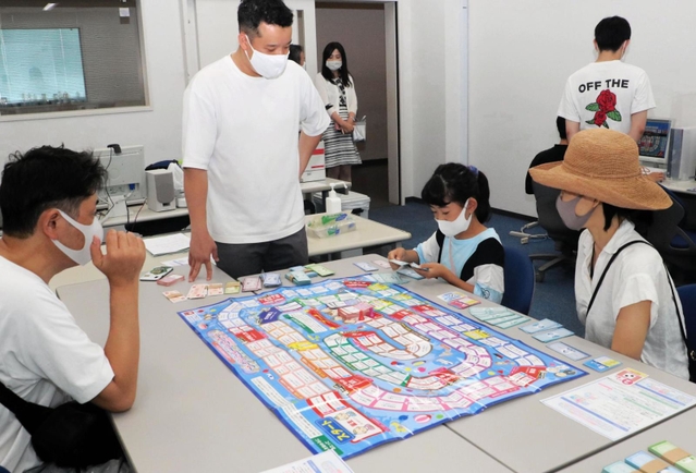 お金の仕組みを学ぶ「ライフシミュレーションゲーム」を体験する親子＝神戸市東灘区向洋町中９