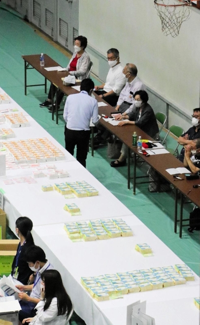 右端に並んで座るのが立会人。ここのチェックも終えた票の束が、左の白い机「集積台」に並べられていく＝１１日未明、神戸市東灘区甲南町５