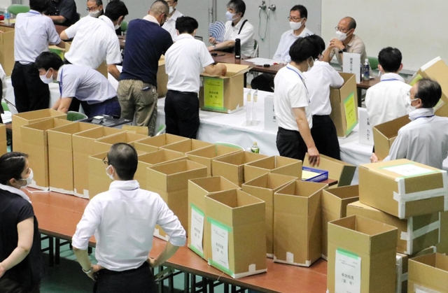 選挙区の開票作業を終え、保管のため段ボール箱に詰めていく職員たち。投票結果が不服で調査を求められたときのため、当選者の任期中は残す＝１１日未明、神戸市東灘区甲南町５