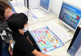 お金の仕組みを学ぶ「ライフシミュレーションゲーム」を体験する親子＝神戸市東灘区向洋町中９
