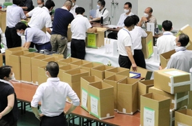 選挙区の開票作業を終え、保管のため段ボール箱に詰めていく職員たち。投票結果が不服で調査を求められたときのため、当選者の任期中は残す＝１１日未明、神戸市東灘区甲南町５