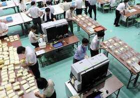 選挙区用には２台の自動読み取り機を使用。紙詰まりなどがあるとすぐ直せるよう、メーカーの職員も立ち会っている＝１０日夜、神戸市東灘区甲南町５