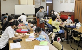高校生が子どもたちの勉強をサポートする西方寺での学習会。中央に立つのが発起人の吉野花さん＝７月下旬、神戸市東灘区御影本町６