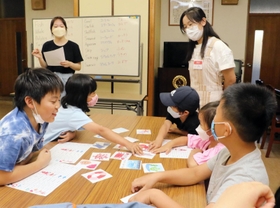 高校生たちが自作した英語かるたで遊ぶ子どもたち＝７月下旬、神戸市東灘区御影本町６