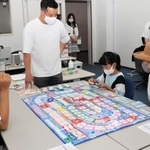 お金の仕組みを学ぶ「ライフシミュレーションゲーム」を体験する親子＝神戸市東灘区向洋町中９