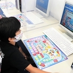 お金の仕組みを学ぶ「ライフシミュレーションゲーム」を体験する親子＝神戸市東灘区向洋町中９