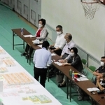 右端に並んで座るのが立会人。ここのチェックも終えた票の束が、左の白い机「集積台」に並べられていく＝１１日未明、神戸市東灘区甲南町５